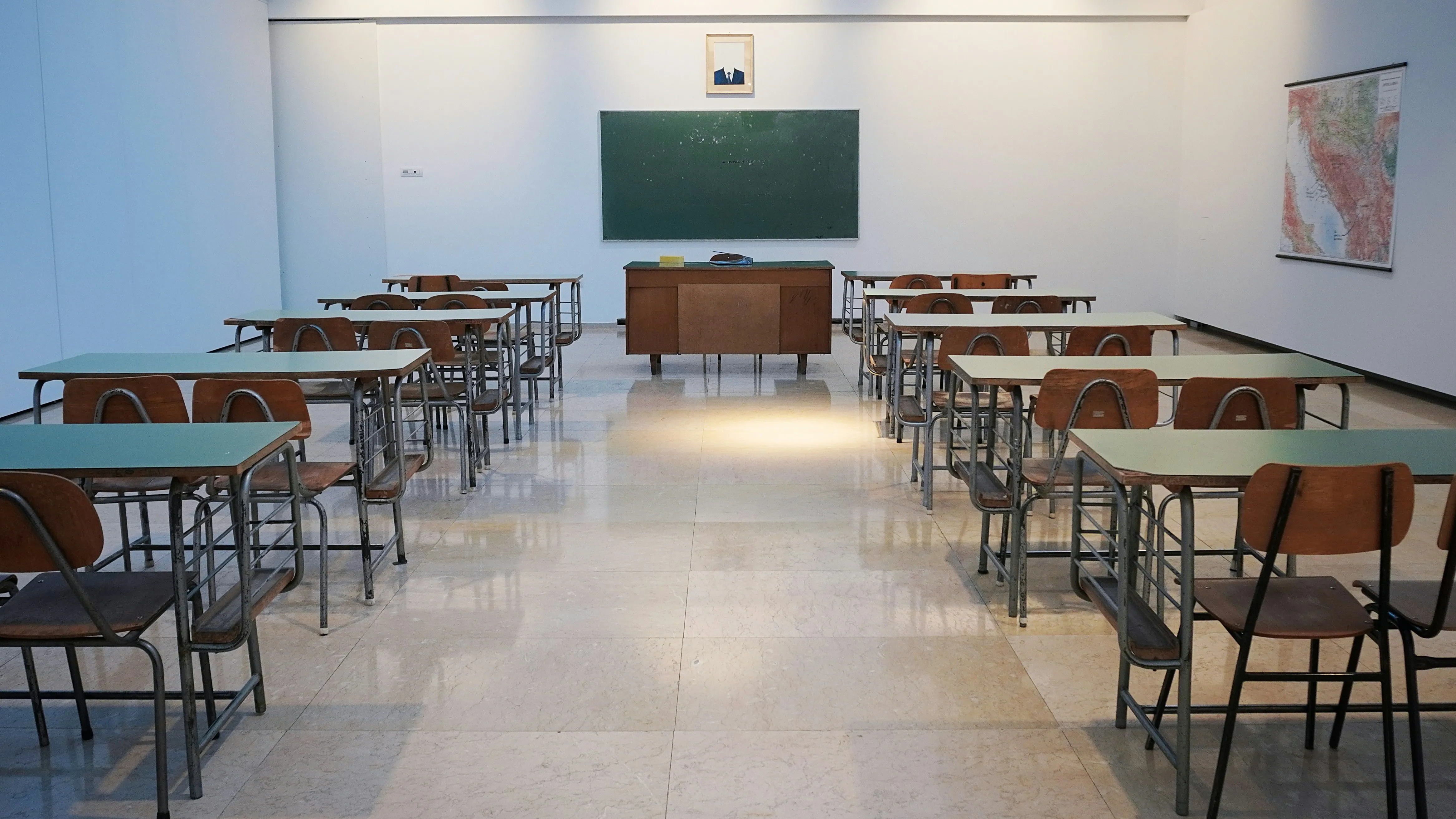 Leerer Klassenraum mit Pulten in Reihen und glänzend gereinigtem Boden — Schule oder öffentliche Einrichtung außerhalb der Unterrichtszeit